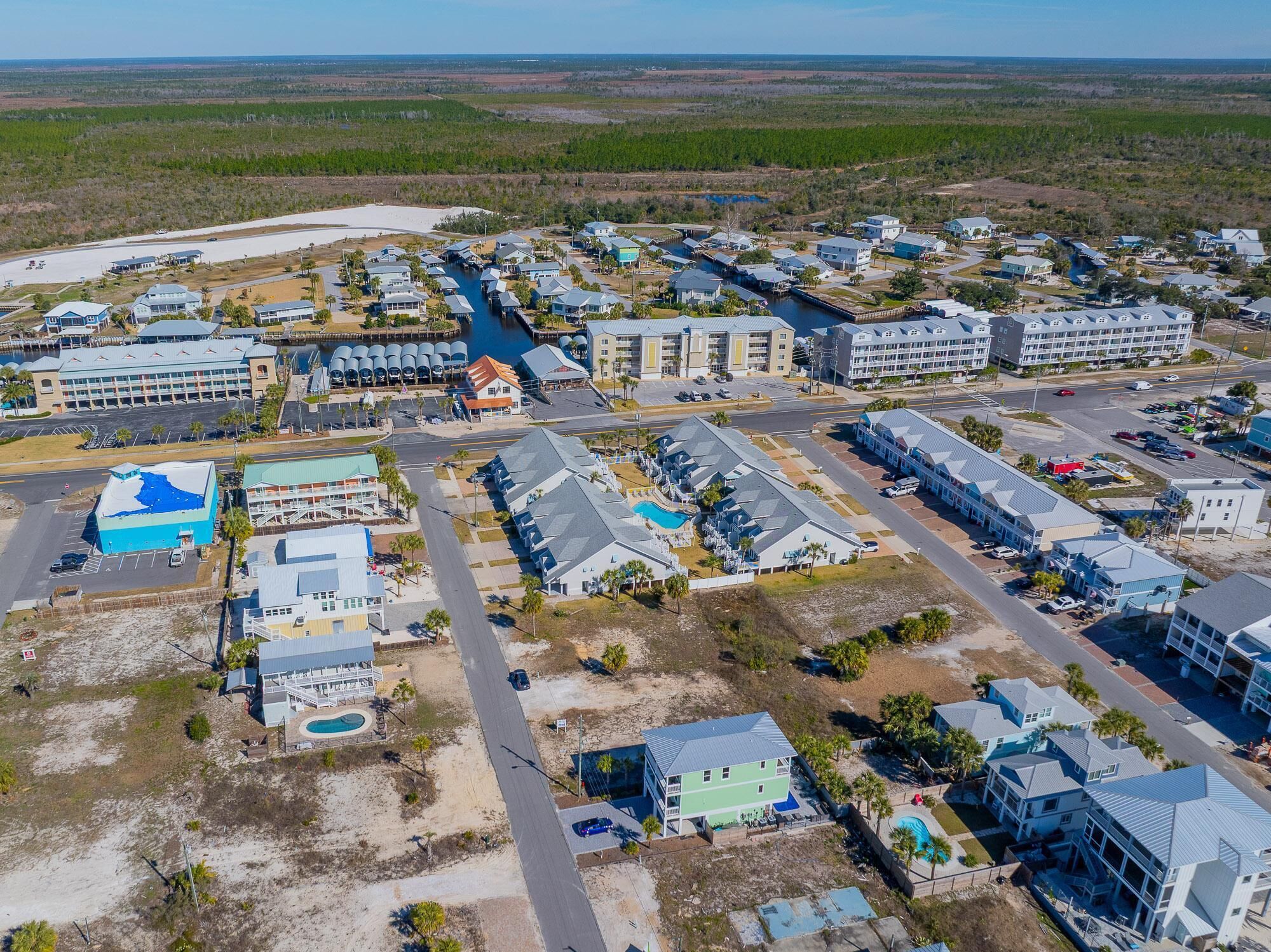 Vue aérienne d’une station balnéaire comprenant plusieurs bâtiments, un port de plaisance et un grand espace piscine.