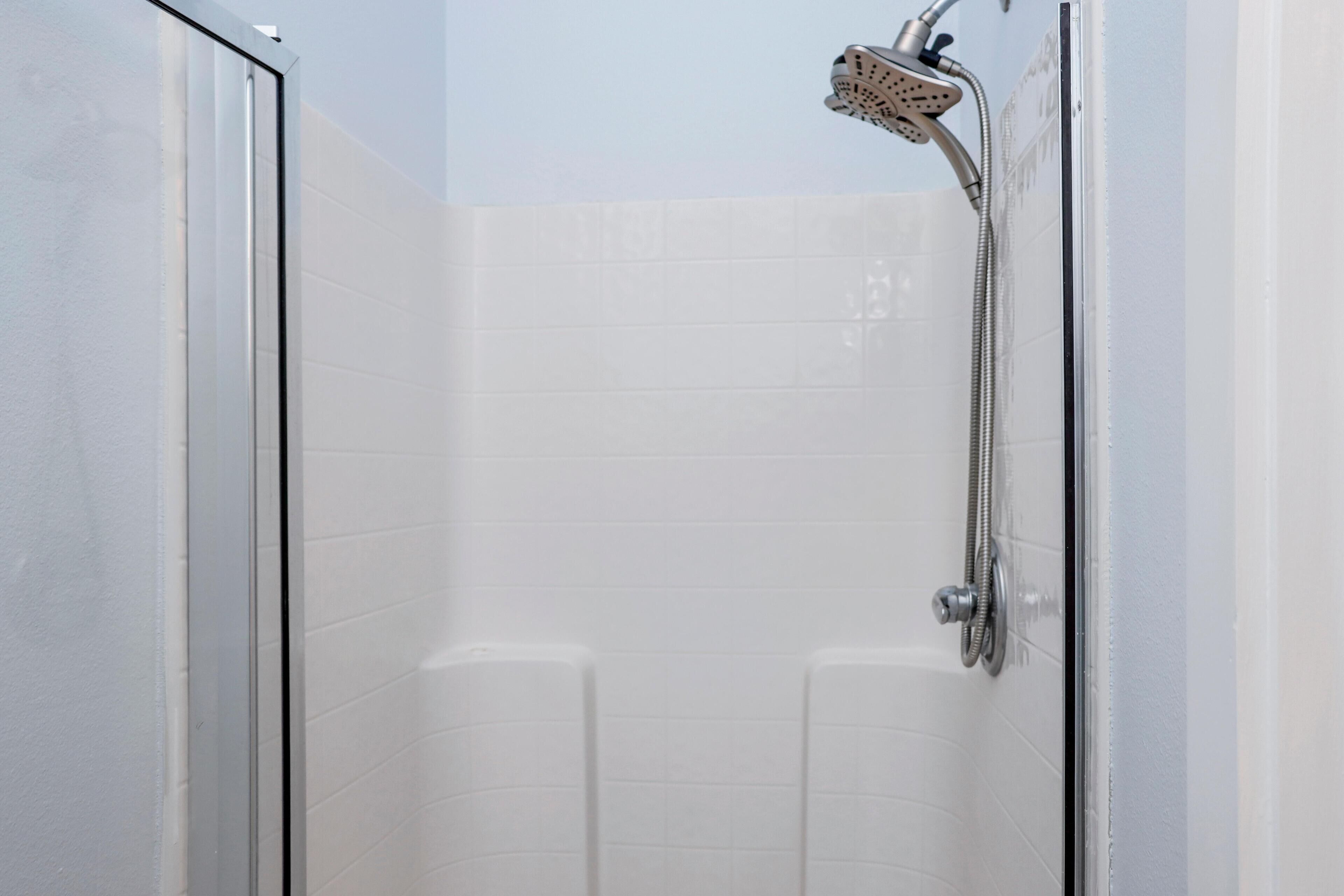 A shower with a handheld showerhead and a wall-mounted faucet.