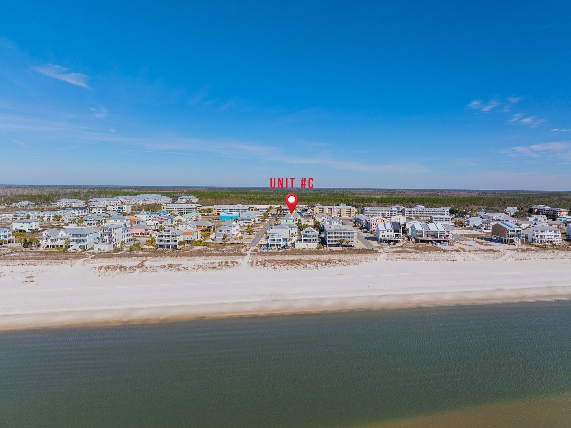 Zona residencial costera con varios edificios, una playa y cielo despejado.