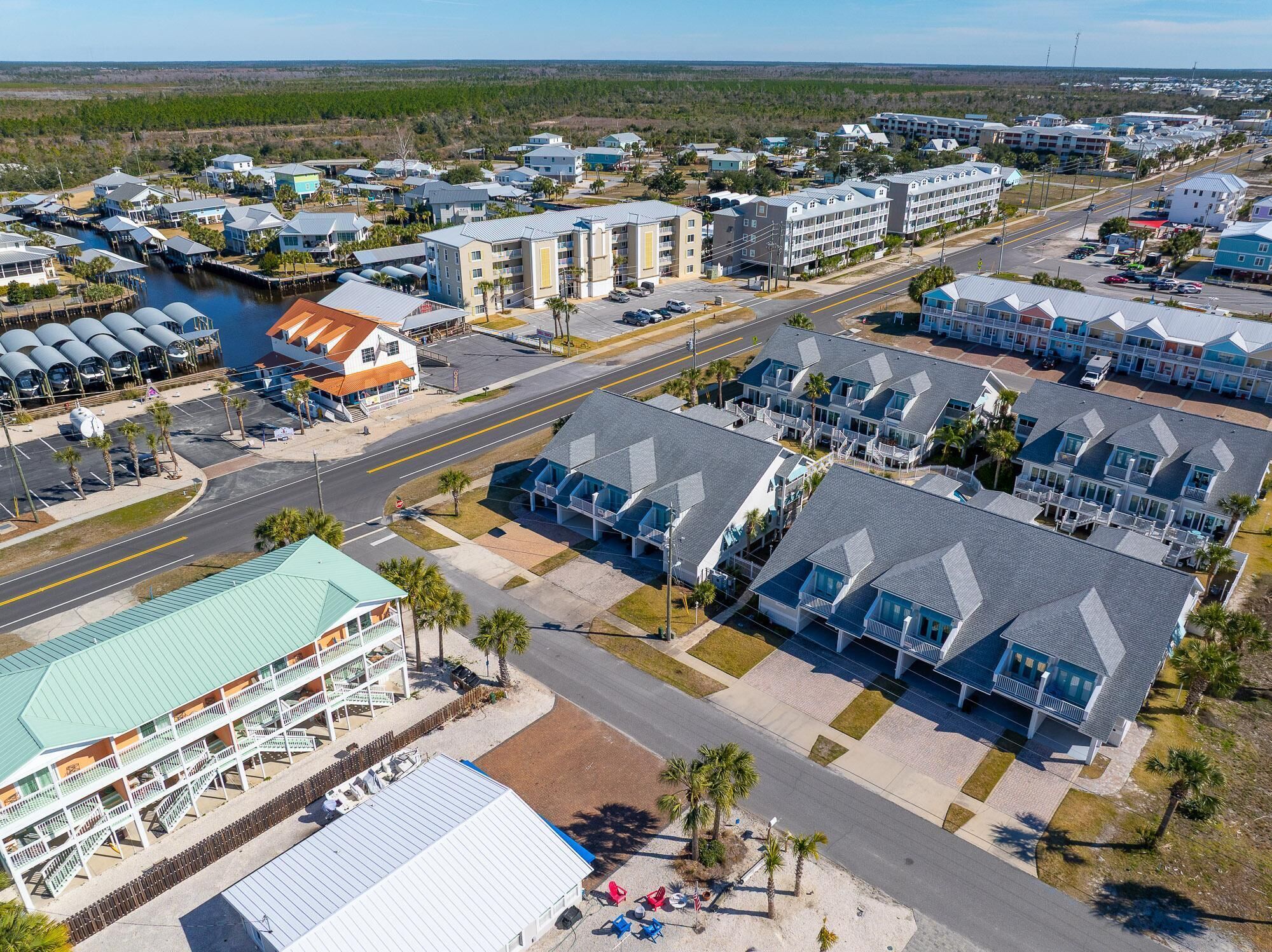 A coastal hotel with multiple-story buildings, a marina, and a road with vehicles.