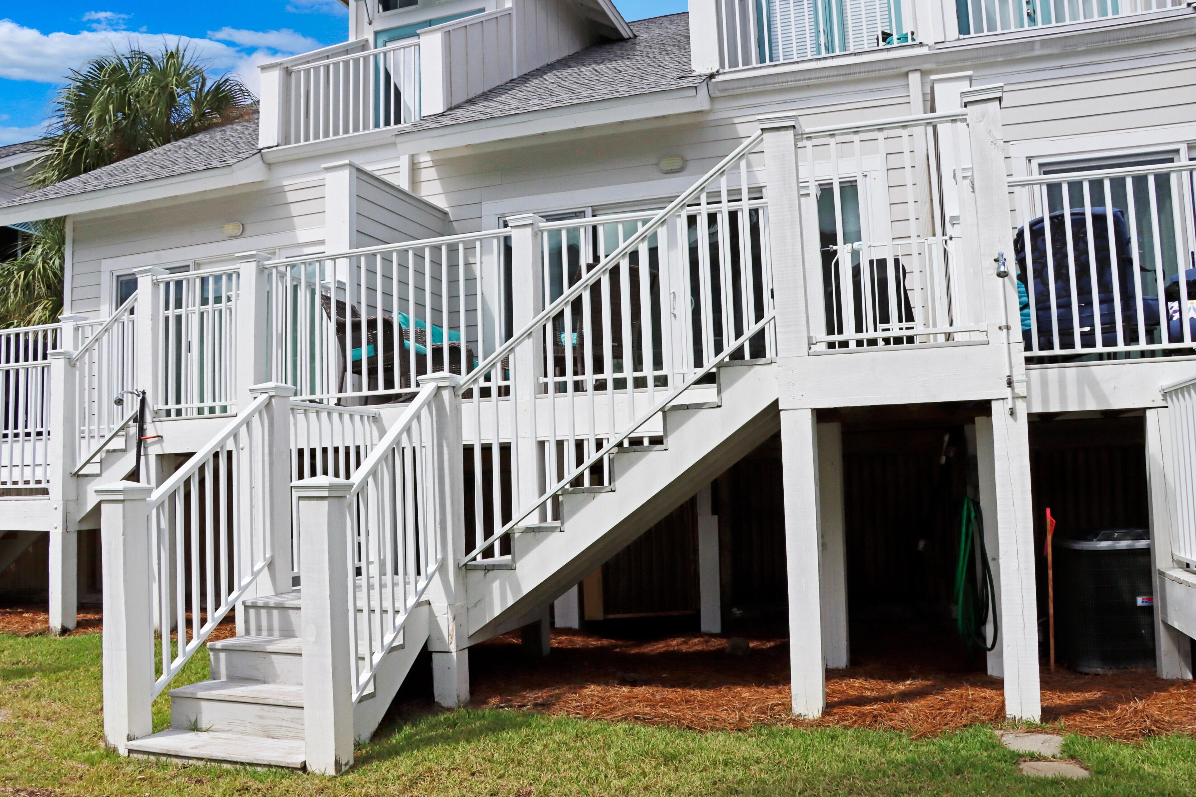 Une maison blanche à plusieurs étages, avec un escalier menant à une terrasse.