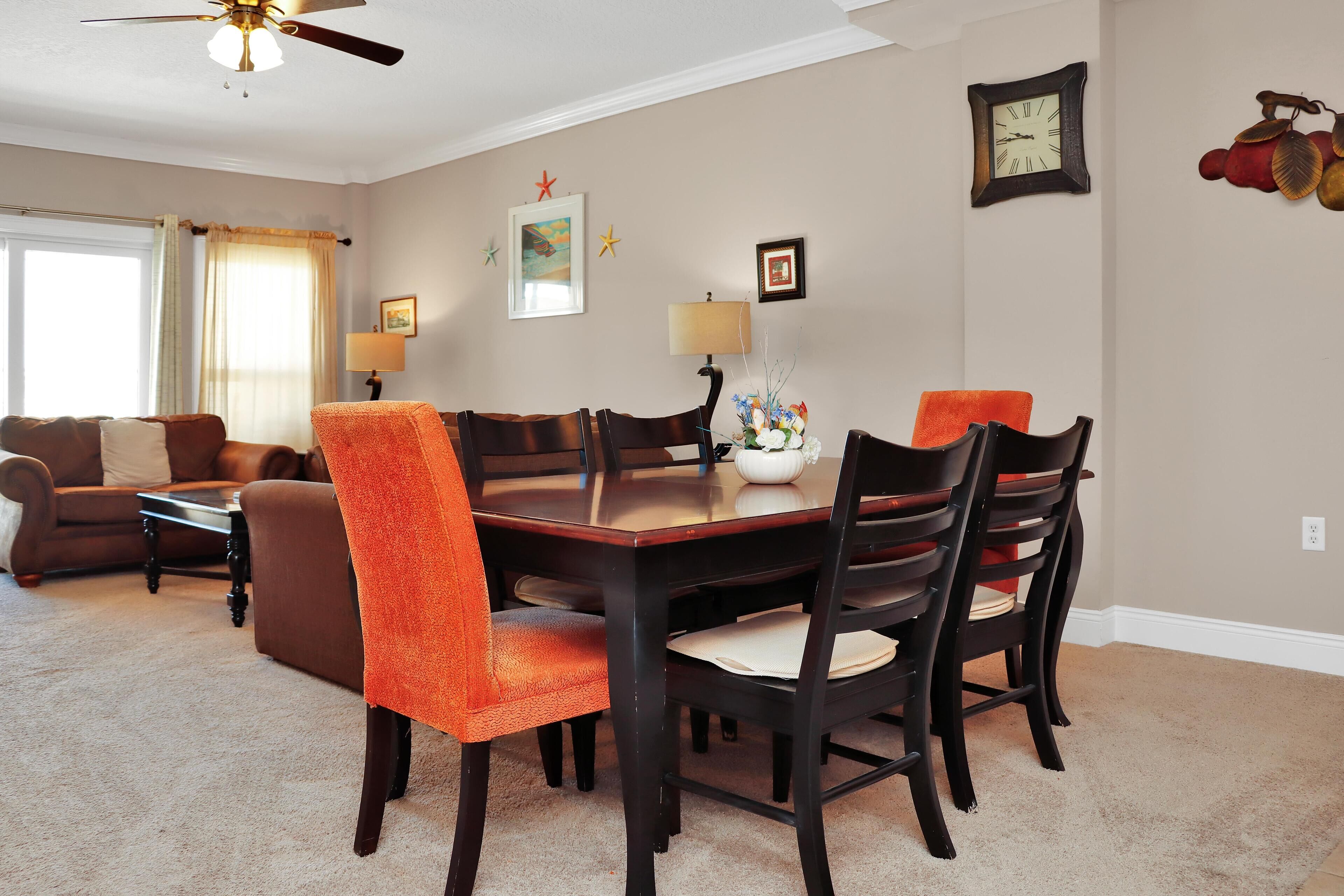 A dining area with a wooden table and chairs, a lamp, and a vase with flowers.