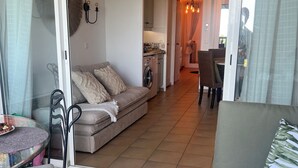 Un espace de vie comprenant un canapé, une table à manger et une cuisine en arrière-plan.