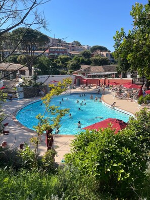 A pool area with multiple swimming pools, sun loungers, and umbrellas.