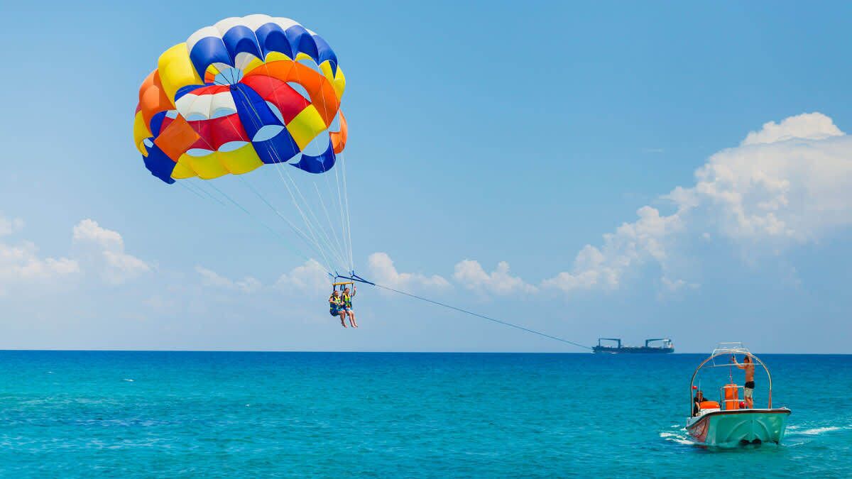 A parasailing activity over turquoise water with a boat in the background.