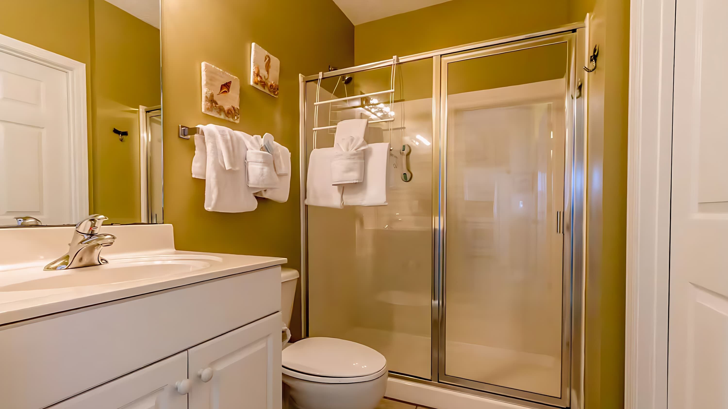 A bathroom with a glass-enclosed shower, a white sink, and a toilet.