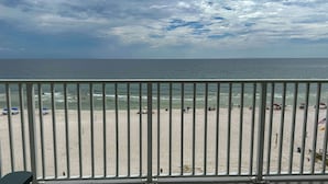 A beach with a metal railing in the foreground, a sandy beach, and the ocean in the background. - Spacious 3-bedroom Beachfront Condo Pool, Large Balcony (Pensacola)