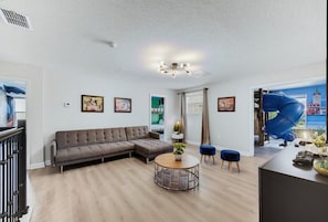 Una sala de estar moderna con un sofá modular, una mesa de centro redonda y un comedor con una silla azul.