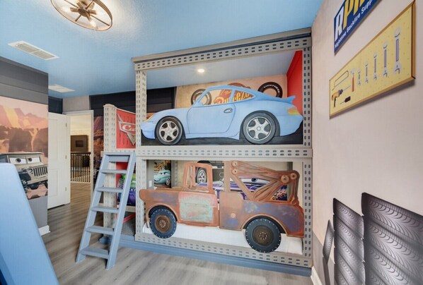 Una habitación con literas, una escalera y una exposición de coches de juguete.