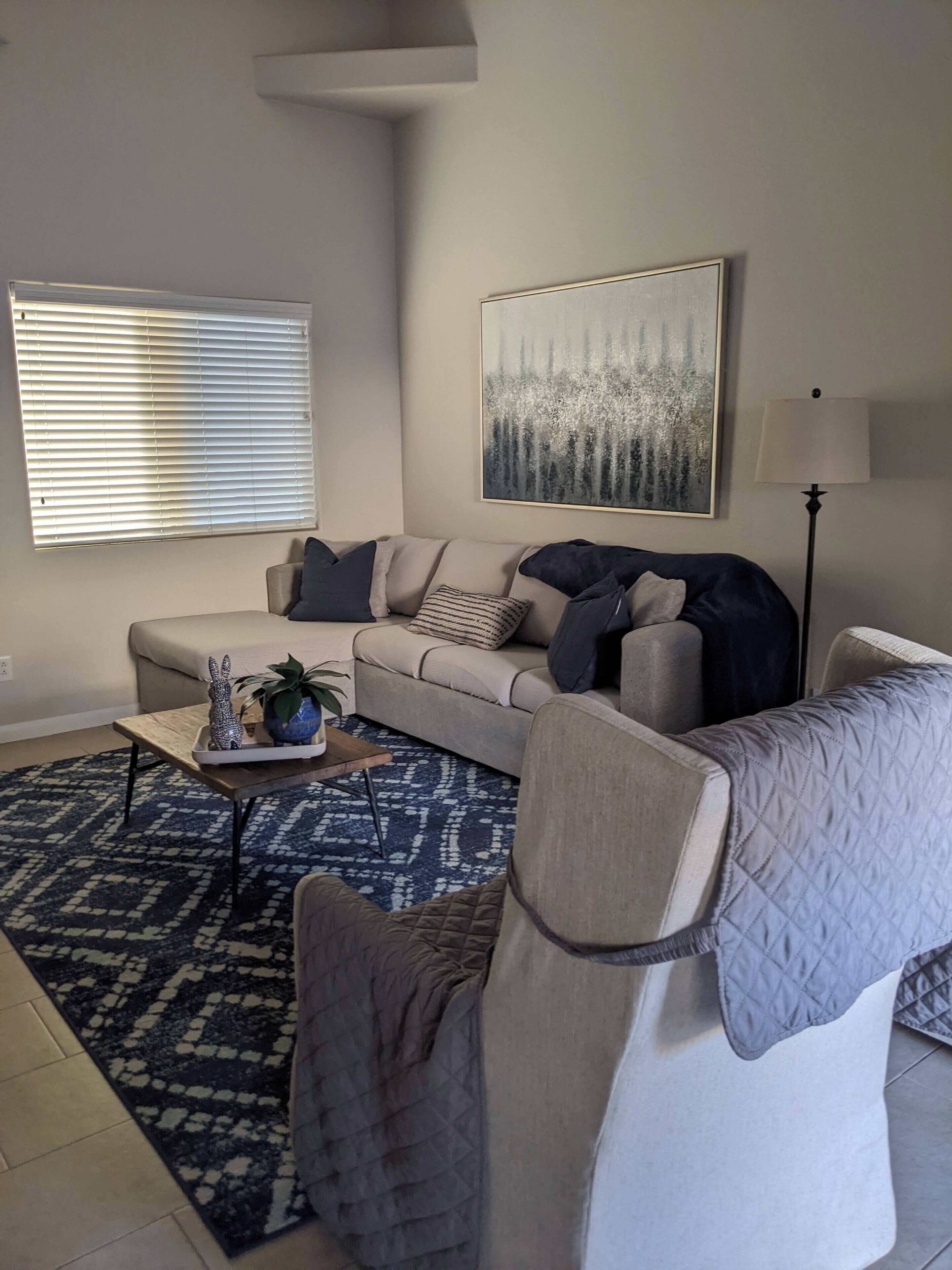 A living room with a sofa, a coffee table, a lamp, and a painting on the wall.
