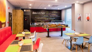 A modern restaurant interior with red seating, a chalkboard menu, and a variety of food displayed. - Ibis Istanbul West (Istanbul)