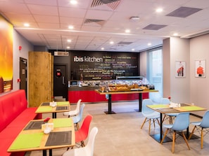 A modern restaurant interior with red seating, a chalkboard menu, and a variety of food displayed. - Ibis Istanbul West (Istanbul)