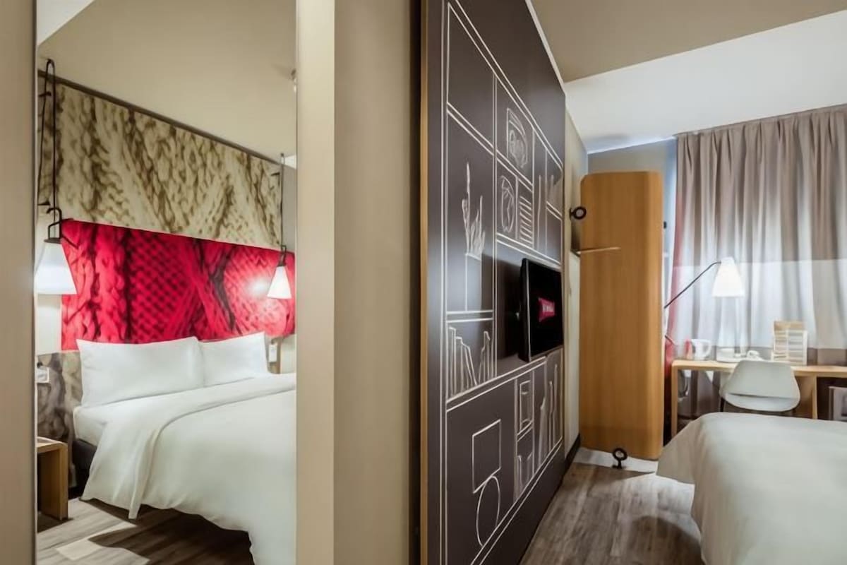 Une chambre d’hôtel équipée d’un lit, d’un bureau, d’une télévision et d’une armoire.