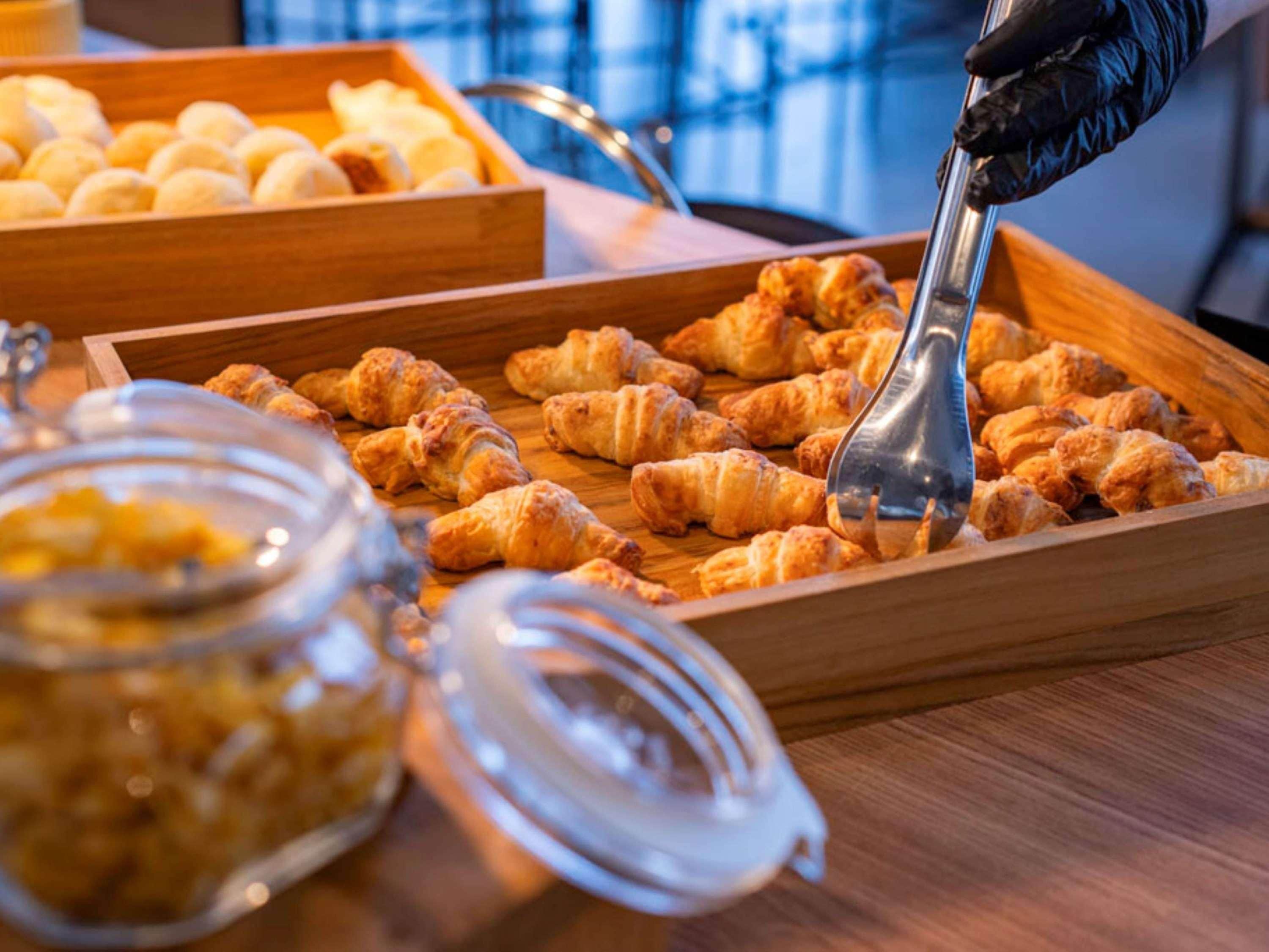 Un vassoio di legno con croissant e un barattolo di marmellata.