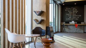 Un interior moderno con mostrador de recepción, zona de estar y una pared con texto.