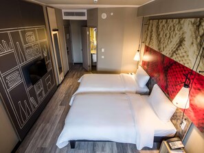 Une chambre d’hôtel comprenant un lit, une table de chevet, une lampe et un mur orné d’un motif texturé.