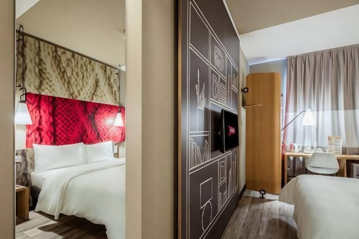 A hotel room with a bed, a desk, a TV, and a wardrobe.