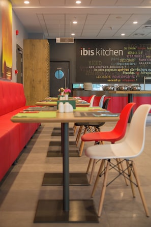 Un restaurant avec un long comptoir, des sièges rouges et un menu écrit à la craie.