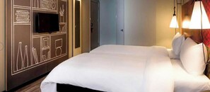 Ein Hotelzimmer mit einem Bett, einem wandmontierten Flachbildfernseher und einer Tür.