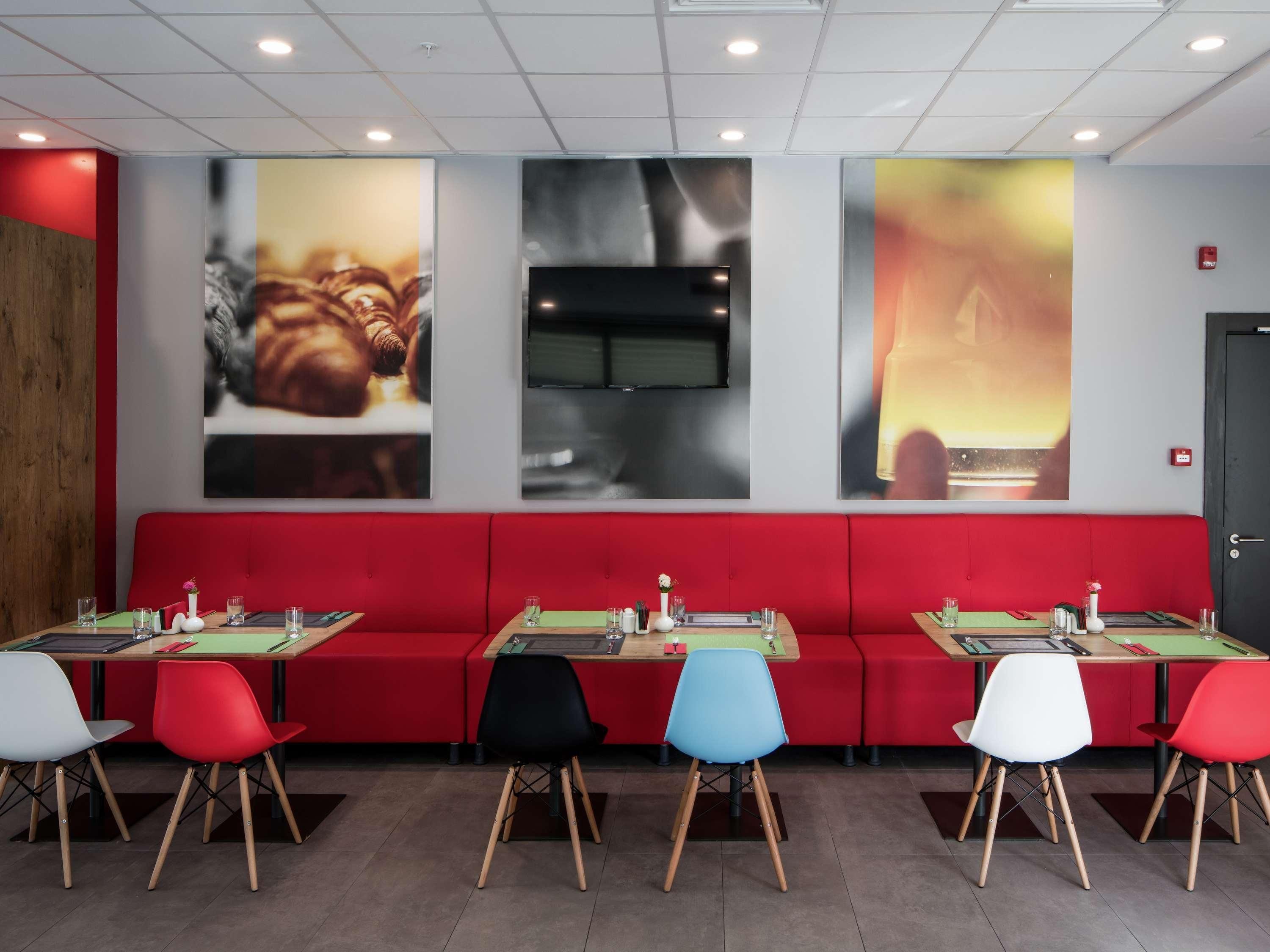 Ein Restaurant mit roten Sitzbänken, mehreren Tischen und Stühlen.
