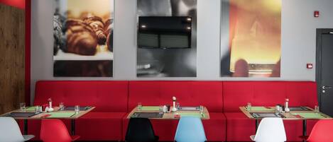 Ein Restaurant mit roten Sitzbänken, mehreren Tischen und Stühlen.