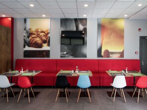 Un restaurant avec des banquettes rouges, de nombreuses tables et des chaises.