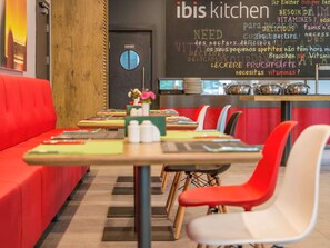 L’intérieur d’un restaurant avec des sièges rouges, un menu écrit à la craie et un mur en bois.