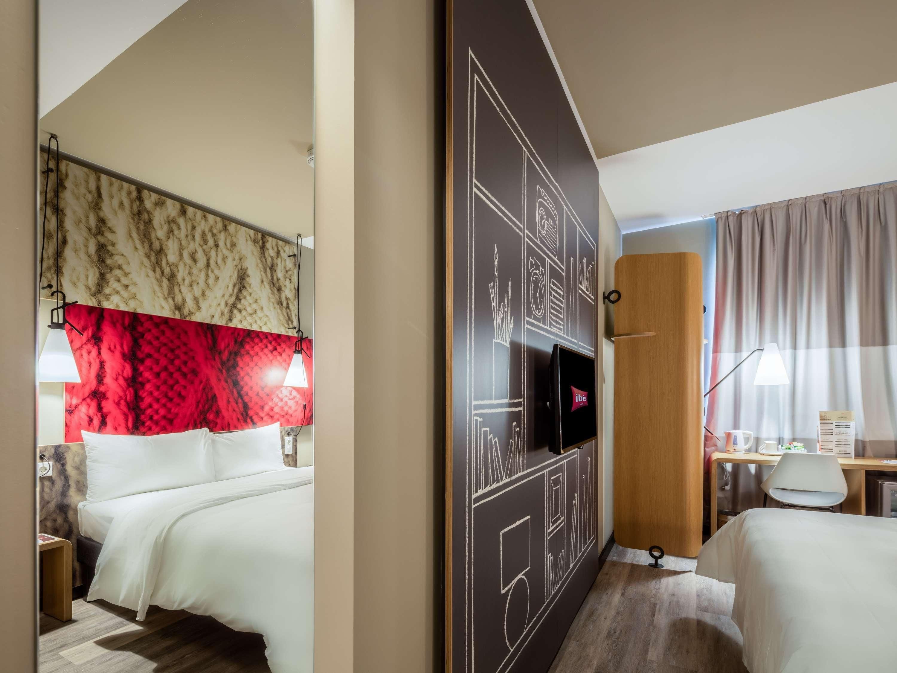 A hotel room with a bed, a desk, a television, and a wardrobe.