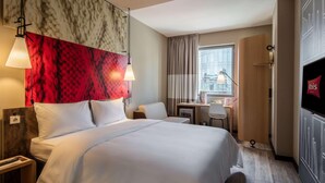 A hotel room with a bed, desk, chair, TV, and a window with curtains. - Ibis Istanbul West (Istanbul)