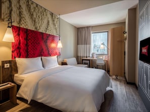 A hotel room with a bed, desk, chair, TV, and a window with curtains. - Ibis Istanbul West (Istanbul)