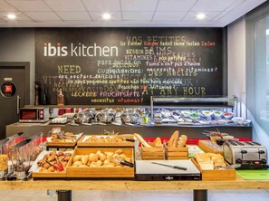 Ett område med en buffé, en meny på en svart tavla, olika sorters mat och en brödrost.
