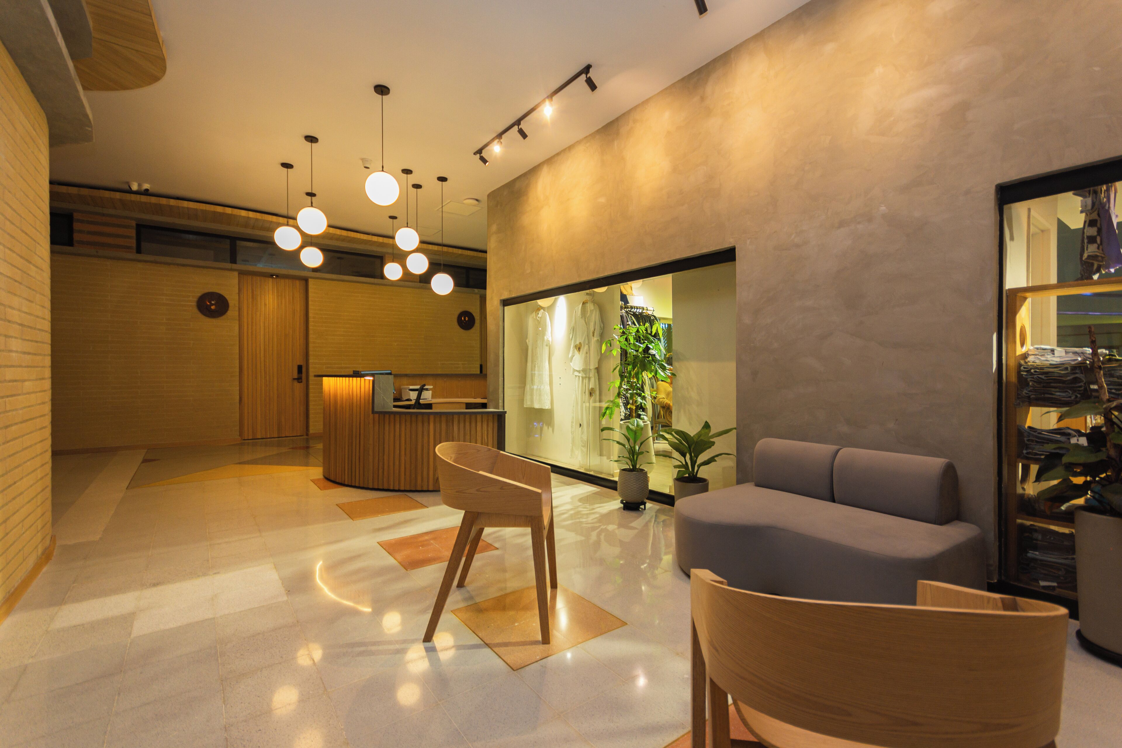 A modern hotel lobby with a reception desk, seating area, and a large mirror reflecting the interior.