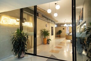 Un hall d’hôtel avec un comptoir d’accueil, des plantes en pot et un design moderne.