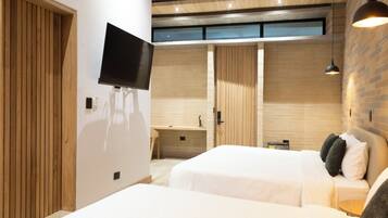 Una habitación de hotel moderna con dos camas, televisión, escritorio y baño con puerta de madera.