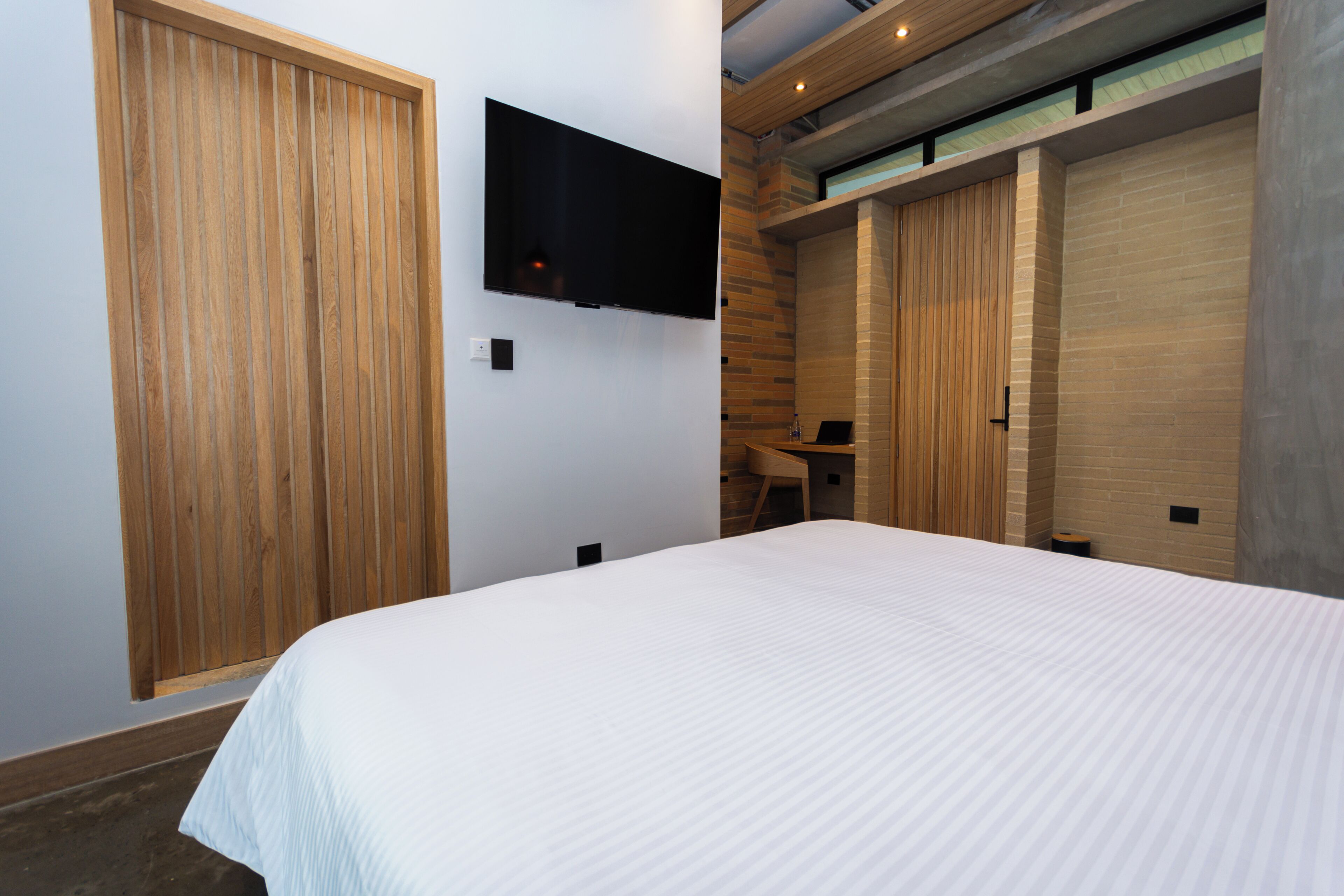 Un dormitorio con una cama grande, un armario de madera y un televisor de pantalla plana montado en la pared.
