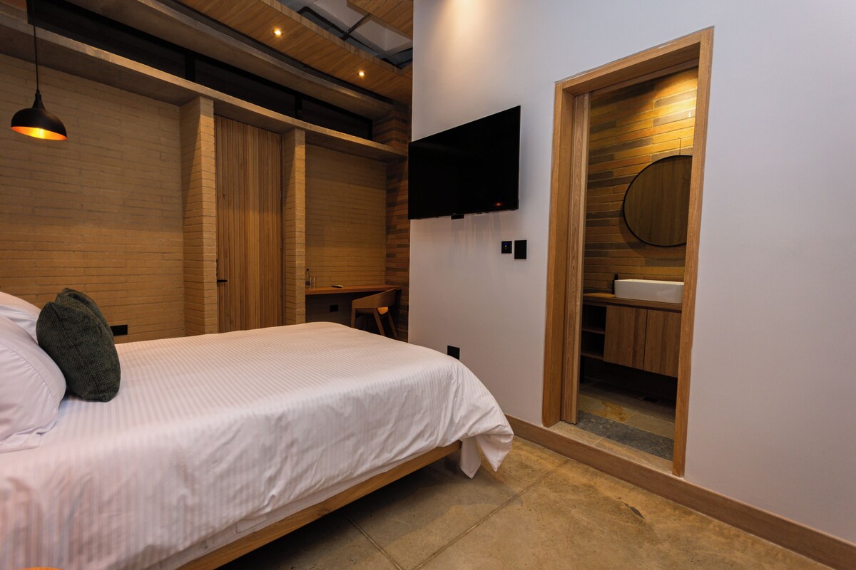 Una camera d'hotel moderna con un grande letto, una TV a parete e un rivestimento murale in legno.