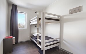 Habitación con literas, una ventana, un escritorio y un aplique de pared.