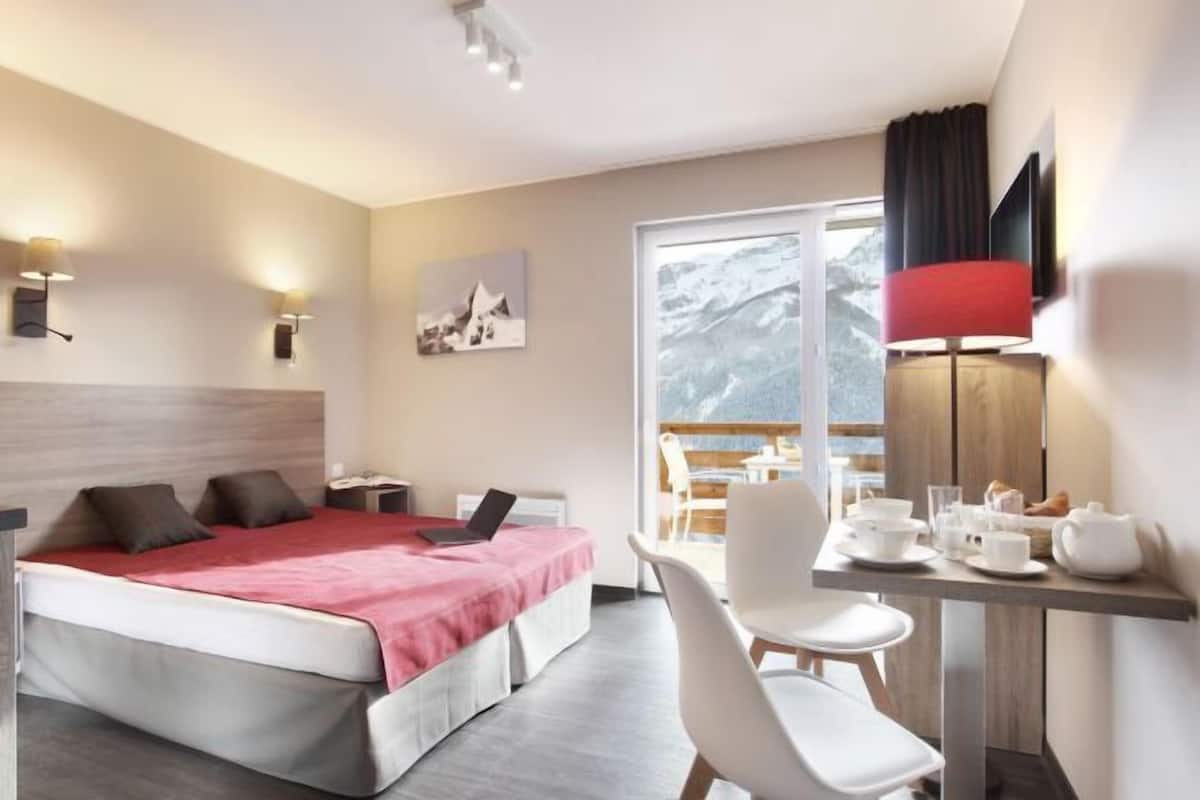 Una habitación de hotel con cama, escritorio, silla y vistas al exterior.