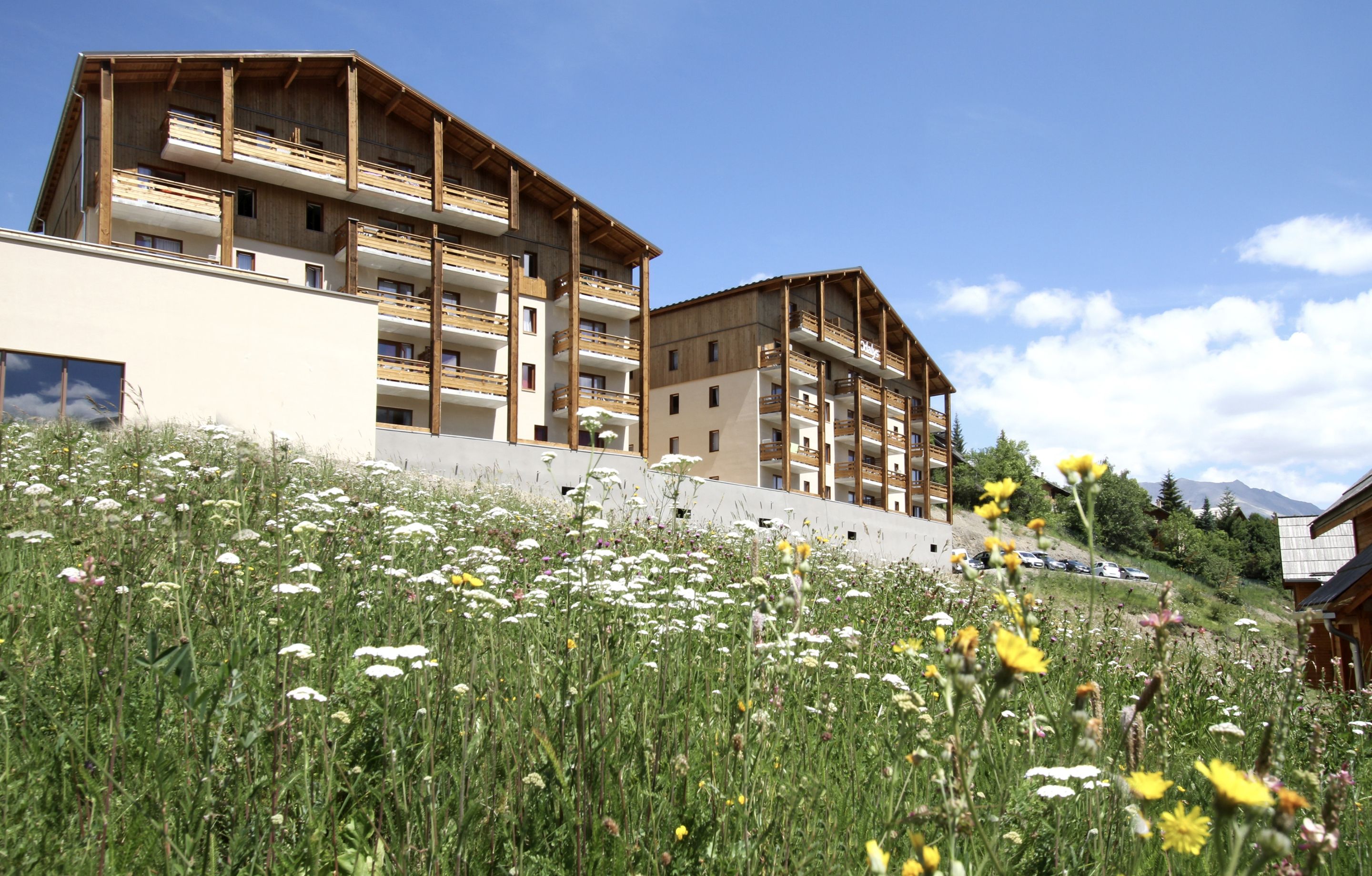 Un hotel de varios pisos con balcones, rodeado por un campo de flores silvestres.