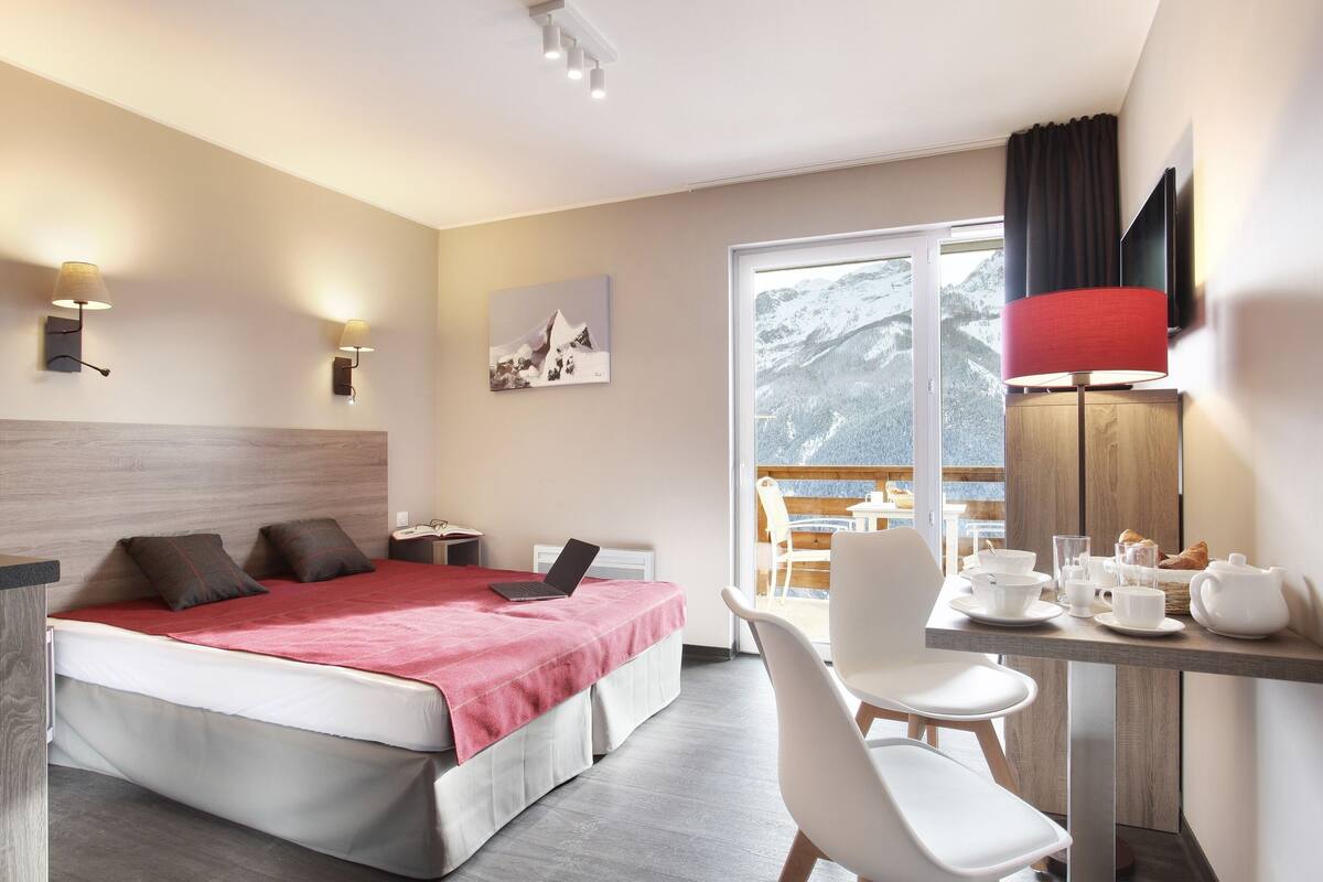 Habitación de hotel con cama, escritorio, silla y vistas a un paisaje nevado.