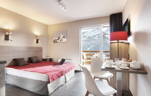 Une chambre d’hôtel avec un lit, un bureau, une chaise et une vue sur un paysage enneigé.