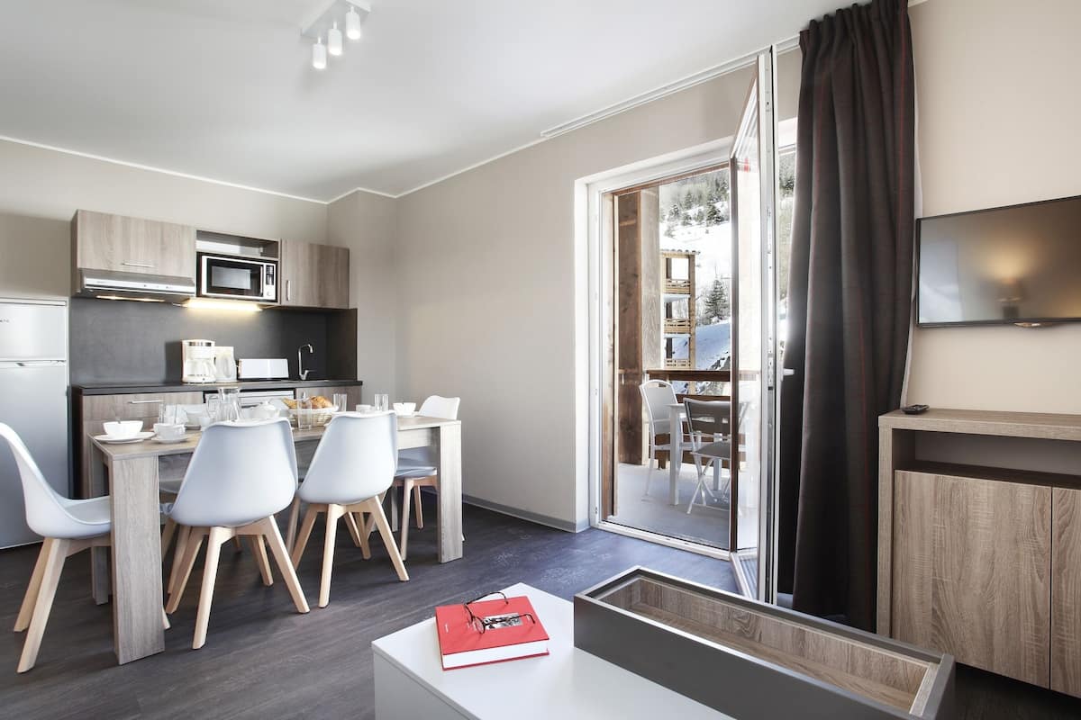 Una cocina moderna con comedor, televisor de pantalla plana y puerta corrediza de vidrio al exterior.
