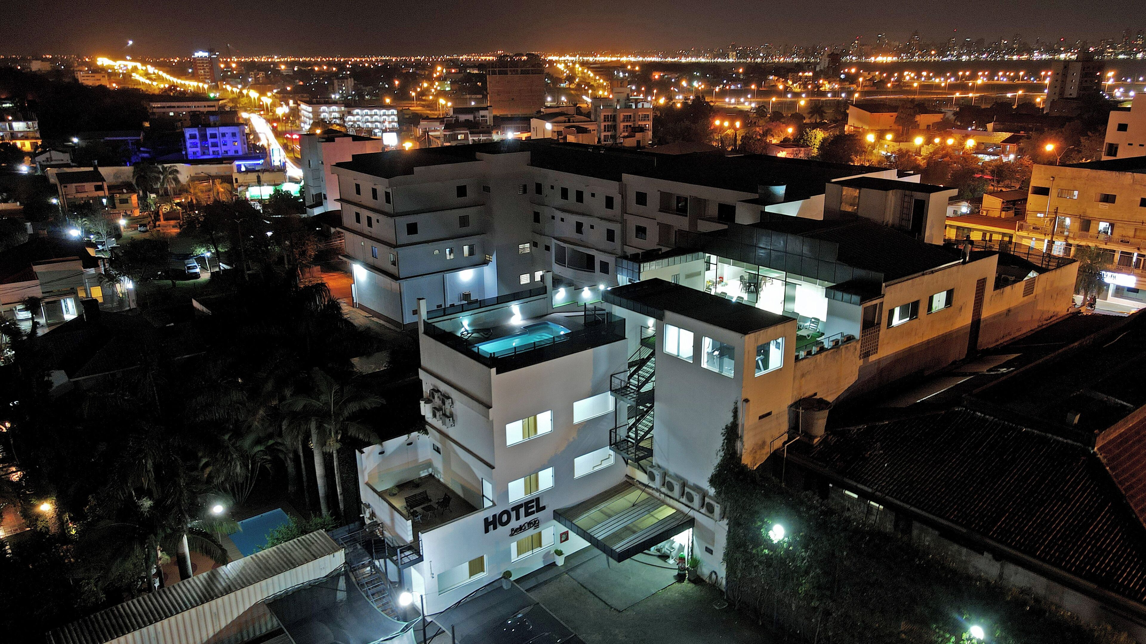 A multi-story hotel with a rooftop pool, a staircase, and a visible entrance.