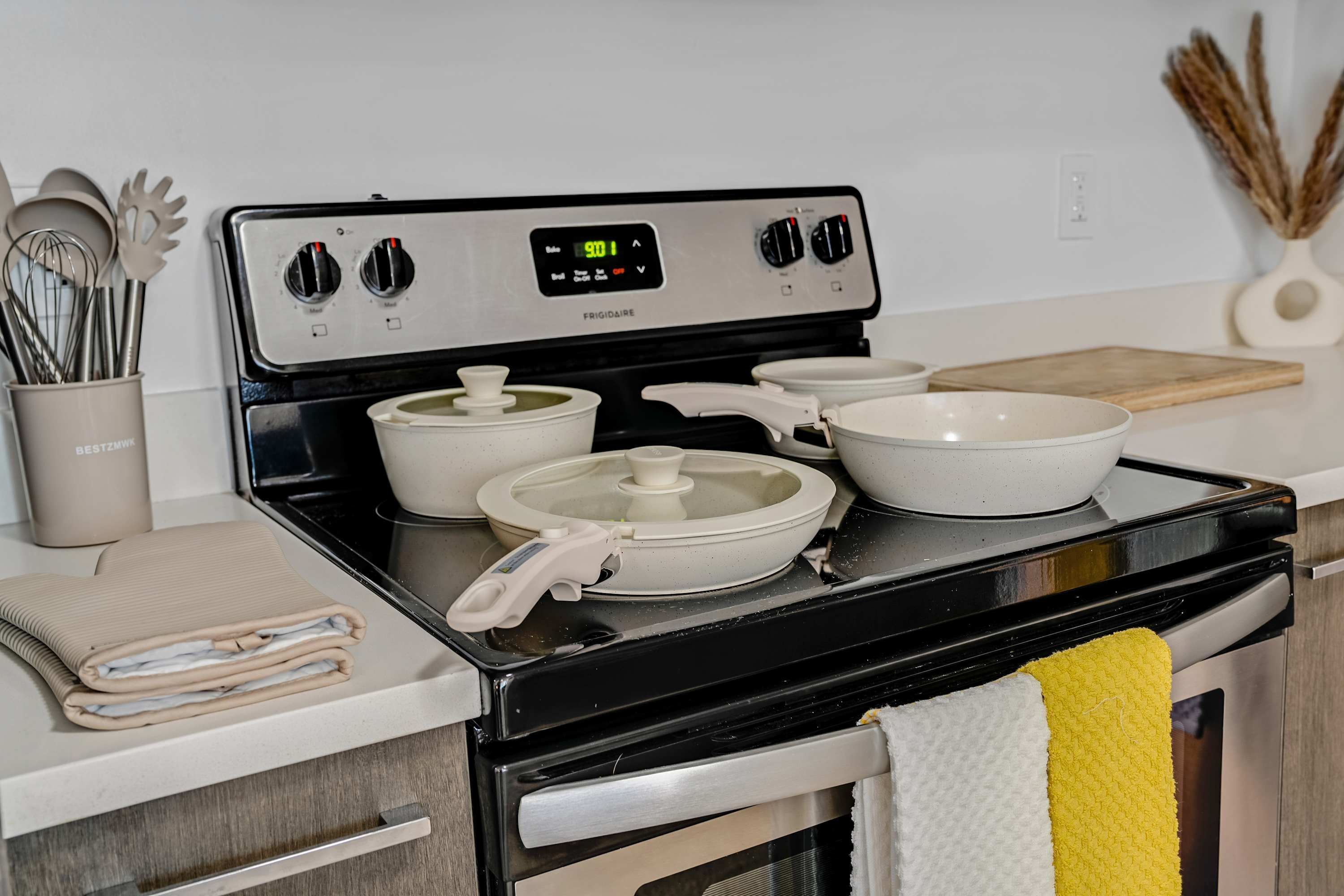 A kitchen with a stove, pots, a cutting board, and a towel hanging on the oven door.