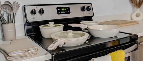 A kitchen with a stove, pots, a cutting board, and a towel hanging on the oven door.