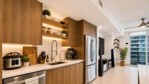 Une cuisine moderne avec des meubles en bois, des appareils électroménagers en acier inoxydable et des étagères intégrées où sont disposées des plantes.