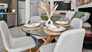 A modern dining area with a glass table, grey upholstered chairs, and a decorative vase with pampas grass. - Downtown Miami Skyline Balcony Penthouse Suite Near Port Luxe Pad (Miami)