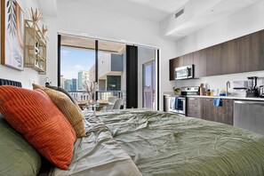 A modern bedroom with a large bed, a balcony with a city view, a kitchenette, and a dining area. - Downtown Miami Skyline Balcony Penthouse Suite Near Port Luxe Pad (Miami)