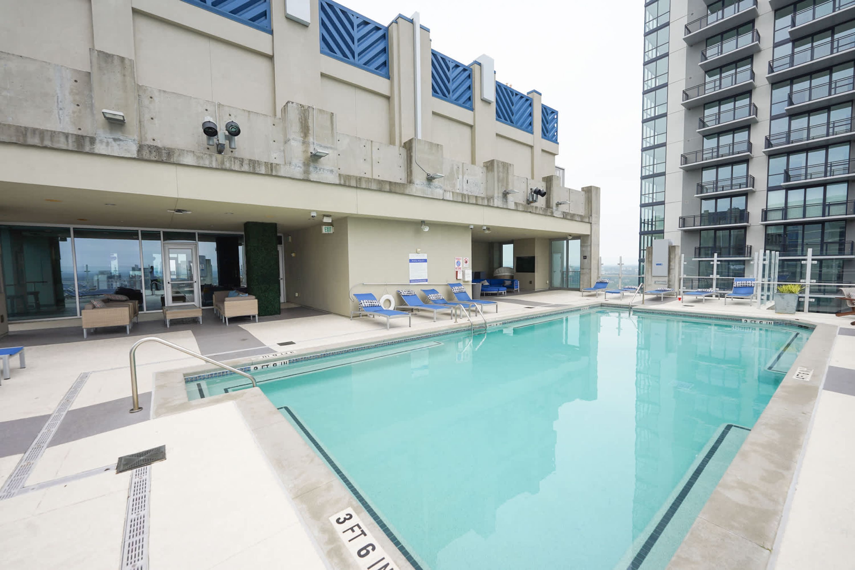 A rooftop pool with lounge chairs and a view of the city.