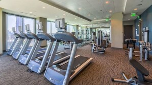 Ein Fitnessstudio mit Laufbändern, Krafttrainingsgeräten und einem Teppichboden.